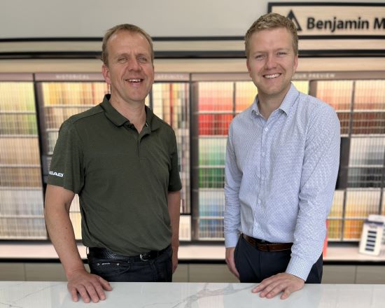 owners of Hamstra Carpet One in front of Benjamin Moore Paint samples